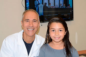 El Dr. Epstein con Chloe, de 7 años, que un día antes se sometió a un procedimiento de trasplante de cabello FUE para reparar las cicatrices del cuero cabelludo. Con sus padres en la sala de procedimientos y su animal de peluche favorito a su lado, lo hizo muy bien! 